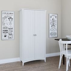 a white cabinet sitting in the corner of a room next to a table and chairs