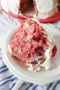 a slice of strawberry cake on a plate with the rest of the cake in the background