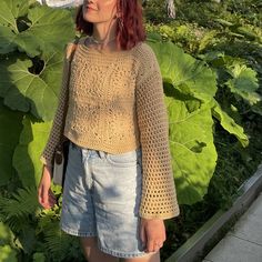 a woman with red hair is standing in front of some plants