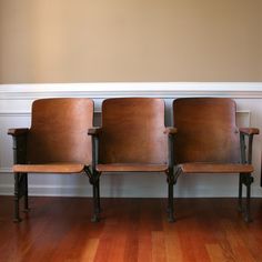 three wooden chairs sitting next to each other on top of a hard wood floor in front of a wall