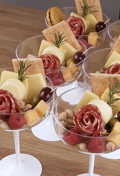 four wine glasses filled with different types of cheese and crackers