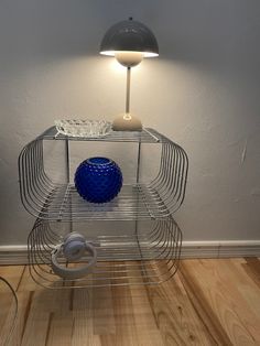 a lamp that is on top of a wire shelf next to a blue vase and headphones