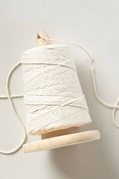 a spool of white thread and a wooden skewer on a white surface