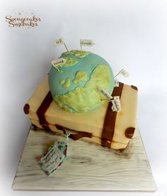 a cake that is shaped like a globe with luggage on top and tags attached to it