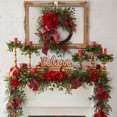 a fireplace decorated for christmas with red and green garlands, pine cones, poinsettis and candles