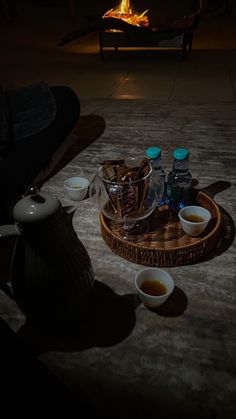 there are bowls and cups on the floor next to an open fire pit with water in it