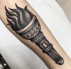 a black and white photo of a tattoo with a torch on it's arm