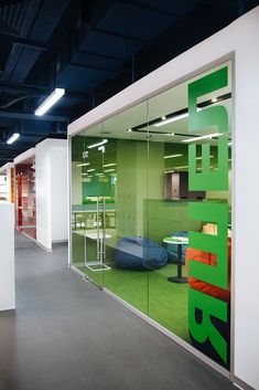 an office with green and white walls, glass partitions, and furniture in the background