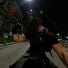 a man riding on the back of a motorcycle wearing a helmet and holding his arm out