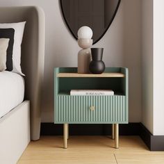 a nightstand with a mirror and vase on it next to a bed in a bedroom