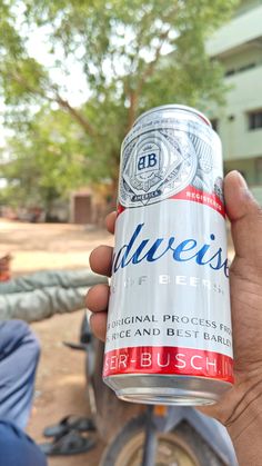 a person holding up a can of budweiser beer