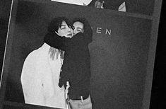 black and white photograph of two people kissing in front of a sign that says given