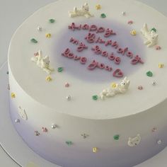 a birthday cake with white frosting and pink lettering