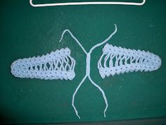 two white crocheted hair clips sitting on top of a green table next to a sign