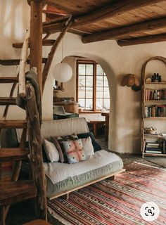 a living room filled with furniture and lots of wooden beams on the ceiling, along with a spiral staircase leading up to an open window