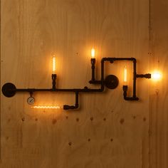 three lights are attached to a wooden wall with pipes and fittings on the side