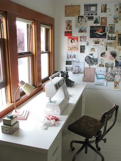 a sewing machine sitting on top of a white desk next to a window filled with pictures