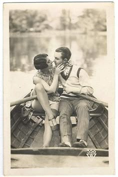 an old black and white photo of two people in a boat kissing on the water