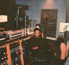 a man sitting in a recording studio surrounded by sound equipment