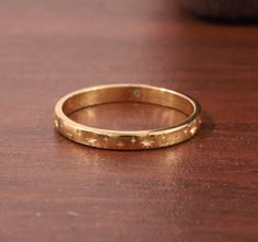 a gold ring with stars on it sitting on top of a wooden table next to a potted plant