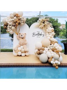 a teddy bear and balloon arch next to a pool