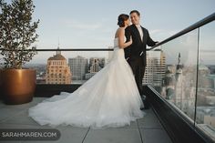 a bride and groom standing on top of a building in front of the city skyline