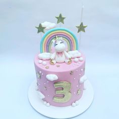 a pink cake with a unicorn on top and stars around the edges, in front of a white background