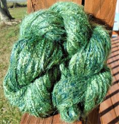 a green ball of yarn sitting on top of a wooden bench