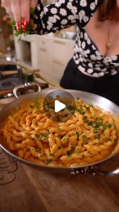 a woman is cooking pasta in a pan