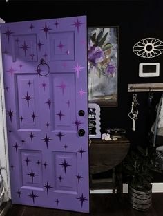 a purple door with stars painted on it in a room next to a desk and chair