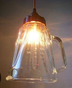 a light that is on top of a glass pitcher hanging from a ceiling fixture in a kitchen