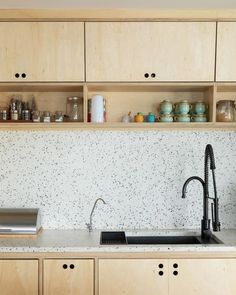 a kitchen with white speckles and wooden cabinetry is seen in this image