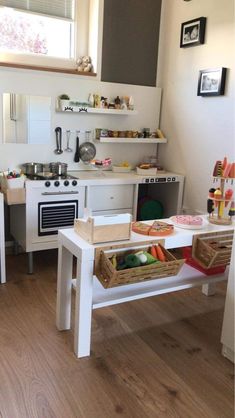 a small kitchen with white appliances and wooden flooring in the center, along with an open window