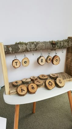 a bench that has some wood slices on it and letters hanging from the back with hooks