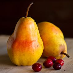 two pears and some cherries on a table