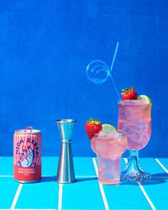 two cocktails with strawberries sit on a table next to a salt shaker