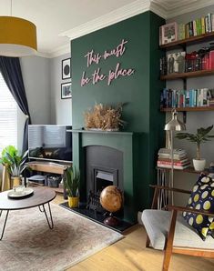 a living room filled with furniture and a fire place in front of a green wall