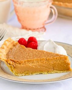 a piece of pie on a plate with raspberries and whipped cream in the background