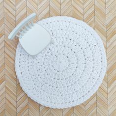 a white crocheted placemat with a plastic fork on it, laying on a wood floor