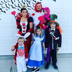 a group of people dressed up as alice and the wonderland characters posing for a photo in front of a garage door