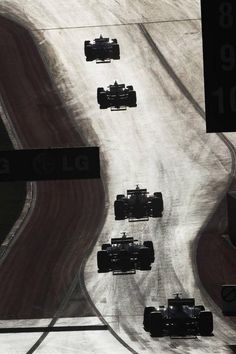 a group of cars driving down a race track in black and white with numbers on the side