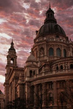 an old building with two towers under a cloudy sky at sunset in the background is a clock tower