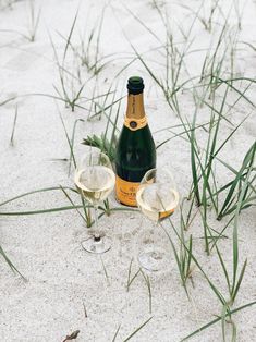 two wine glasses and a bottle in the sand