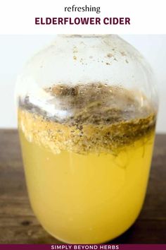 a jar filled with elderflower cider sitting on top of a wooden table