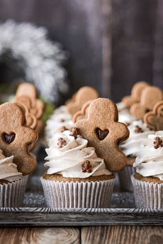 some cupcakes with icing and teddy bears on them sitting on a tray