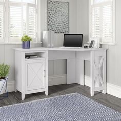 a white desk with a laptop on top of it next to a potted plant