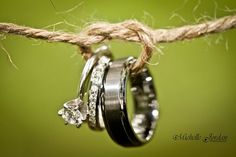 three wedding rings hanging from a rope with two diamonds on them and one diamond in the middle