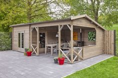 a small wooden shed sitting in the middle of a yard with potted plants on it