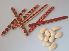 four wooden sticks with different designs on them next to peanuts and other things that are made out of wood