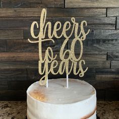 a white cake with gold lettering that says cheers to 40 years